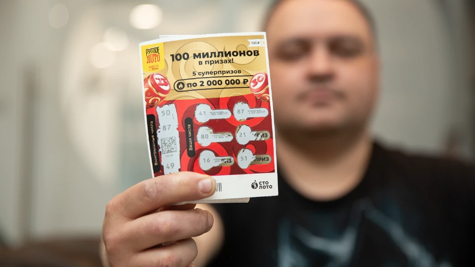 Победитель Дмитрий показывает выигрышный билет моментальной лотереи от «Столото»