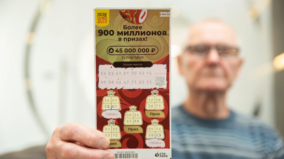 Михаил Дмитрик показывает выигрышный билет моментальной лотереи